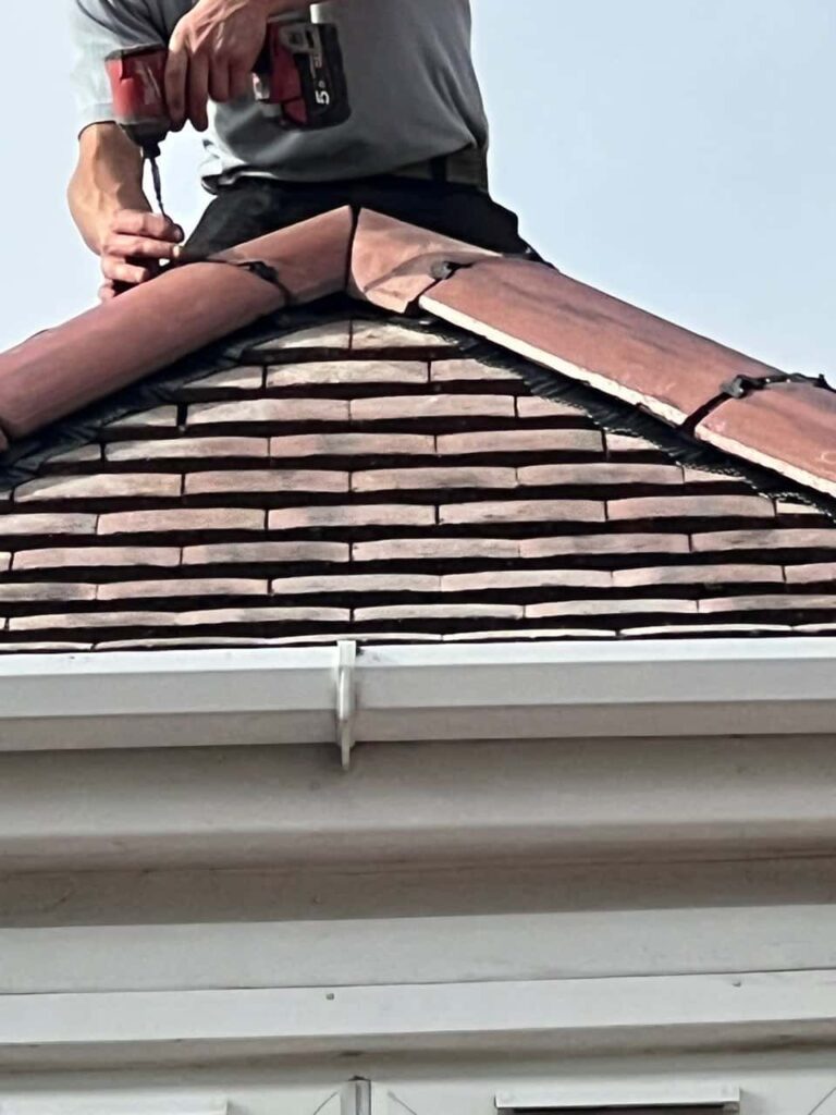 This is a photo of one of the operatives of MCM Roofing Repairs Devizes installing new ridge tiles